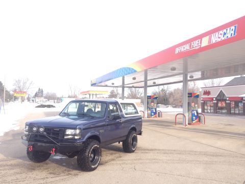 1996 Ford Bronco - A blue 1996 Ford Bronco is parked at a gas station under a NASCAR branded awning.