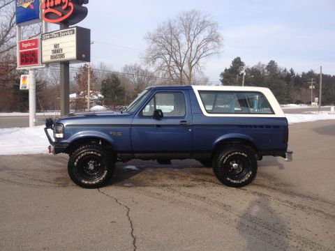 1996 Ford Bronco - This 1996 Ford Bronco, seen from the side, is parked in front of a restaurant with a drive-thru service sign.