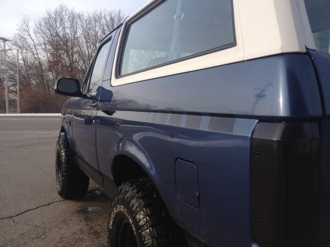 1996 Ford Bronco - Side view of a blue SUV with a white roof, identified as a 1996 Ford Bronco.