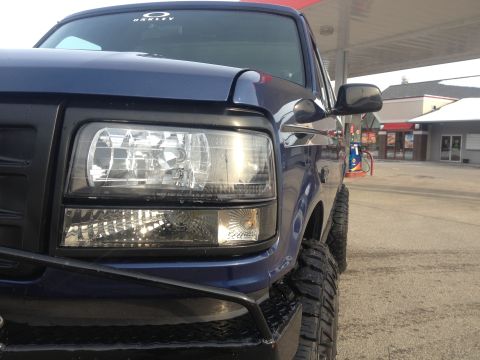 1996 Ford Bronco - Front corner view of a blue pickup truck with aftermarket modifications.