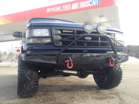 1996 Ford Bronco - This modified Ford truck is parked at a gas station with NASCAR branding on the canopy.
