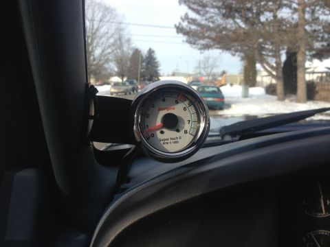 1996 Ford Bronco - A Sunpro Super II tachometer gauge is visible inside a vehicle, with a street scene outside.