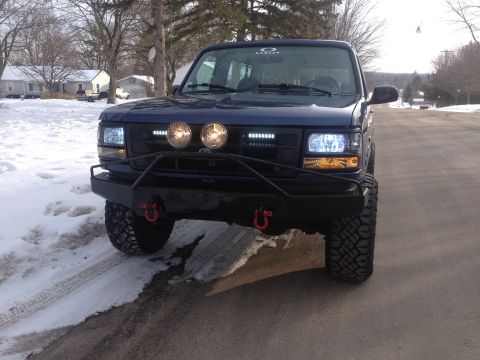 1996 Ford Bronco - Front view of a modified Ford Bronco with large tires and auxiliary lighting, seen in a winter setting.