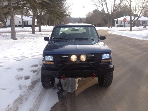 1996 Ford Bronco - This blue Ford F-Series truck is equipped with a heavy-duty bumper and auxiliary lighting, seen in a winter setting.