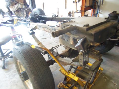 1968 Ford Bronco - Vehicle frame and fuel tank assembly on a jack, likely for a Bronco gas tank modification.