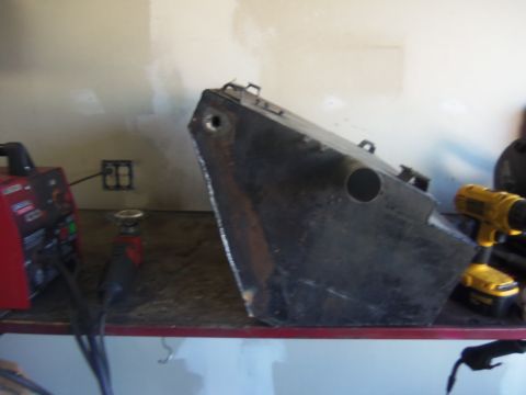 1968 Ford Bronco - A black gas tank sits on a workbench next to a welder and a drill, suggesting modification or repair work.