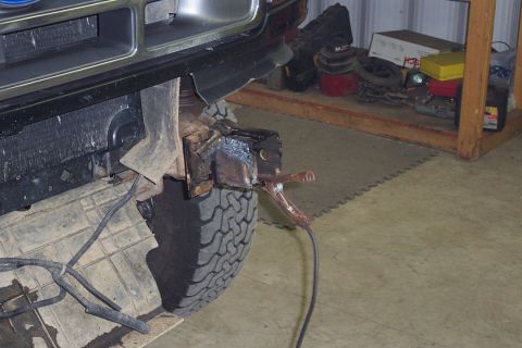 1996 Ford Bronco - A Ford Bronco's front bumper area shows modifications with a welding clamp attached to a bracket.