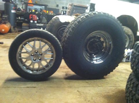 1995 Ford F-150 - Two tires and wheels are displayed in a garage setting.