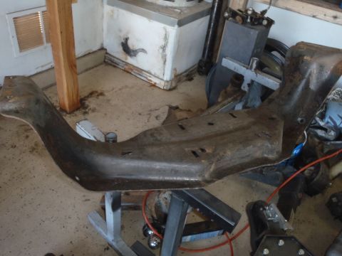 1978 Ford Bronco - A rusted metal frame part is shown on a stand in a garage setting.
