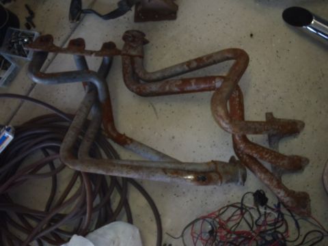 1978 Ford Bronco - Exhaust manifolds are shown with a coiled hose and wiring on a concrete floor.