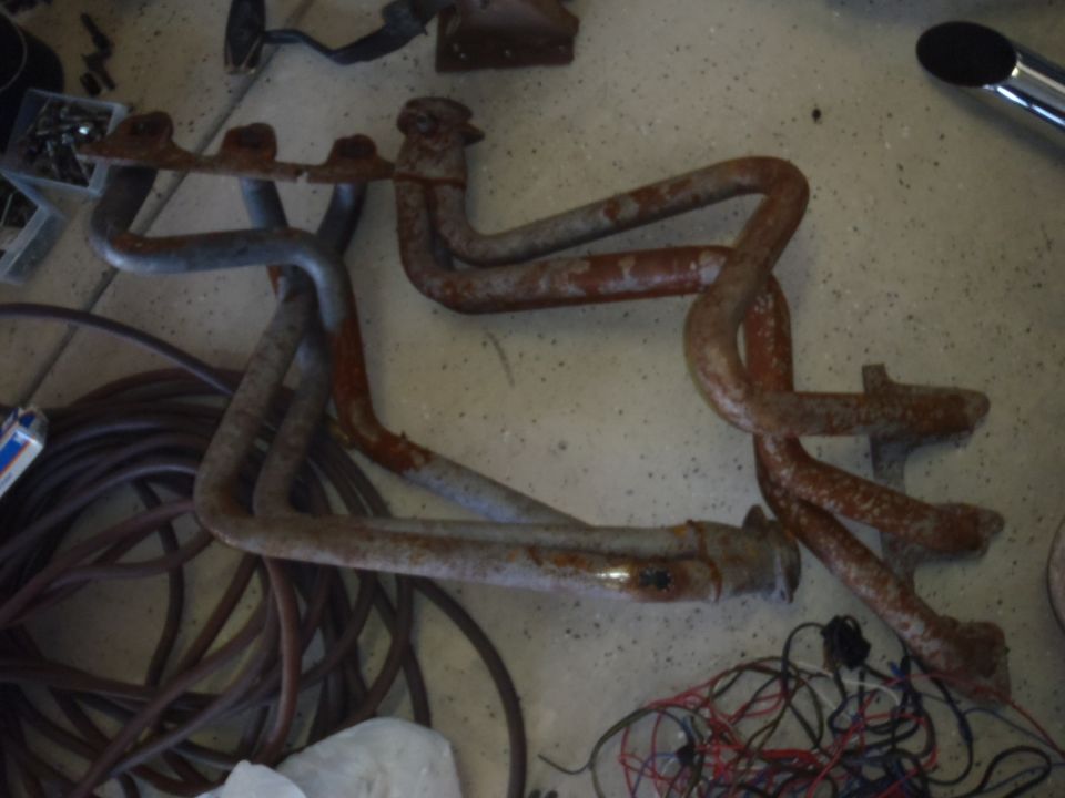 Rusty exhaust manifolds with a coiled hose and wiring on a concrete floor
