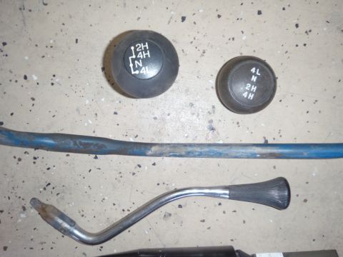 1978 Ford Bronco - Transfer case shifter knobs and levers are shown laid out on a speckled floor.