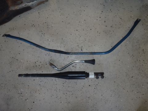 1978 Ford Bronco - Various parts, including a blue sway bar, shifter, and black exhaust pipe, are laid out on a concrete floor.