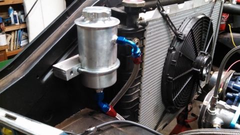 1967 Ford F-250 - Aftermarket power steering reservoir and electric cooling fan assembly in an engine bay.