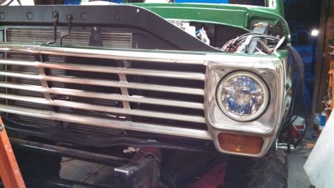 1967 Ford F-250 - Close-up of a green truck's front end, showing the grille and headlight detail of the headlight.