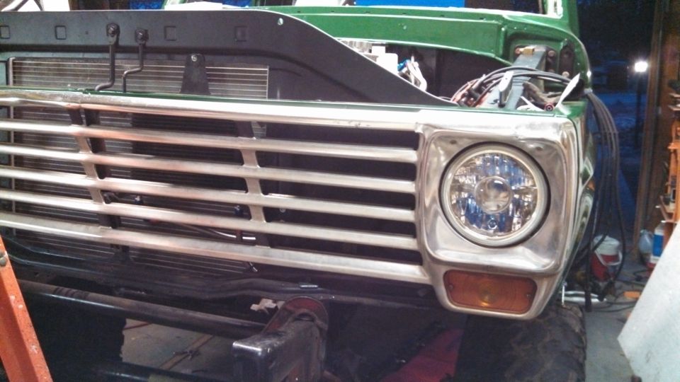 Green truck front grille and headlight assembly, chrome trim, in workshop