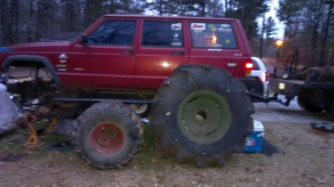 1978 Ford Bronco - Modified Jeep Cherokee XJ with oversized tractor tires, parked outdoors.