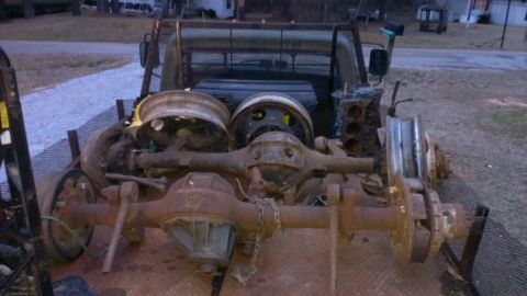 1978 Ford Bronco - Several heavily rusted truck axles and wheels are loaded onto a trailer, along with a disassembled engine block.