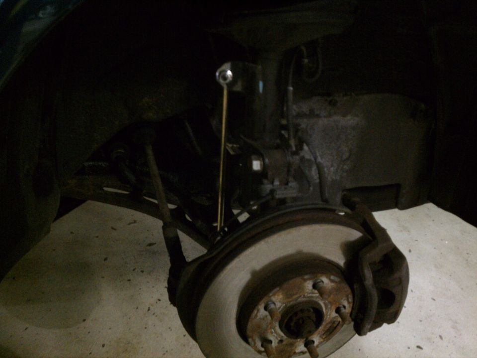 Car's front wheel assembly with brake rotor and caliper visible