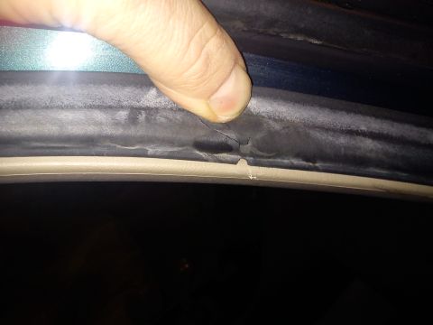 1998 Toyota Camry - Close-up of a damaged rubber seal on a car's door frame, indicating a need for repair.