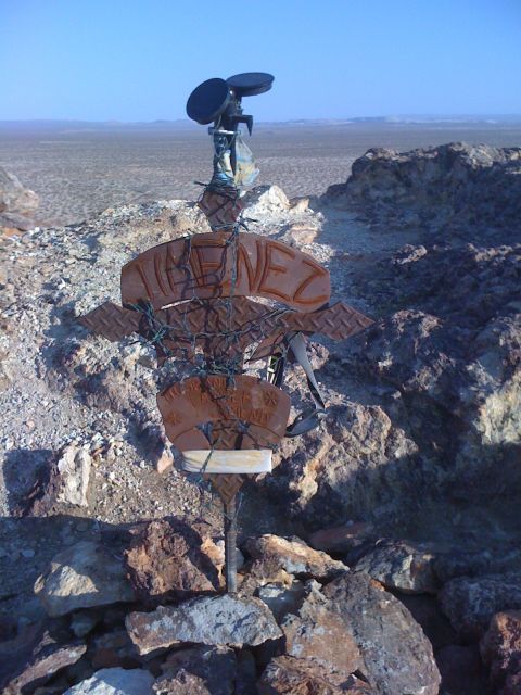 1986 Yugo GV - A unique desert monument constructed from scrap metal and adorned with various signs and artistic elements.