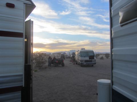 1986 Yugo GV - An RV and an off-road vehicle are parked in a desert campground during sunset.
