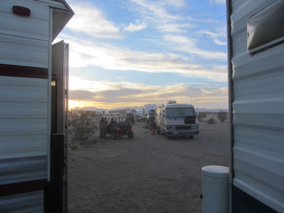 Desert campground scene with RV and off-road vehicle at sunset