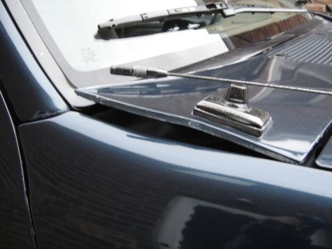 1996 Ford Bronco - Close-up view of the hood ornament and windshield wiper assembly on a dark blue 1996 Ford Bronco.