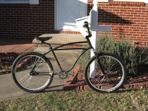 1994 Ford Bronco - A black bicycle with a curved frame and knobby tires is parked next to a mailbox and brick house.