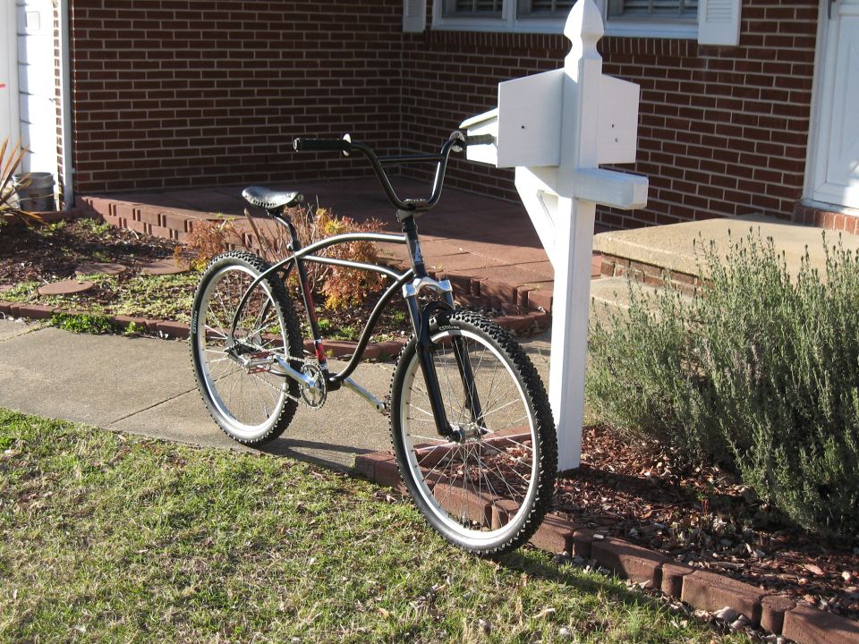 Cruiser bicycle with wide handlebars parked next to a white mailbox