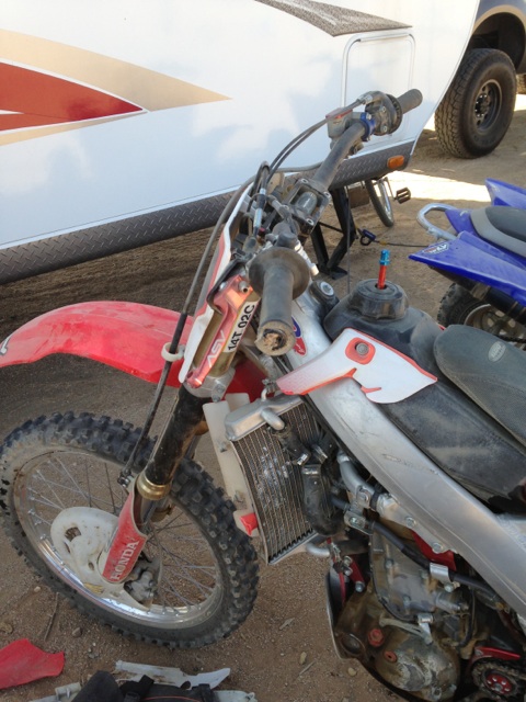 1986 Yugo GV - A dirt bike is parked next to a trailer, with another ATV visible in the background.