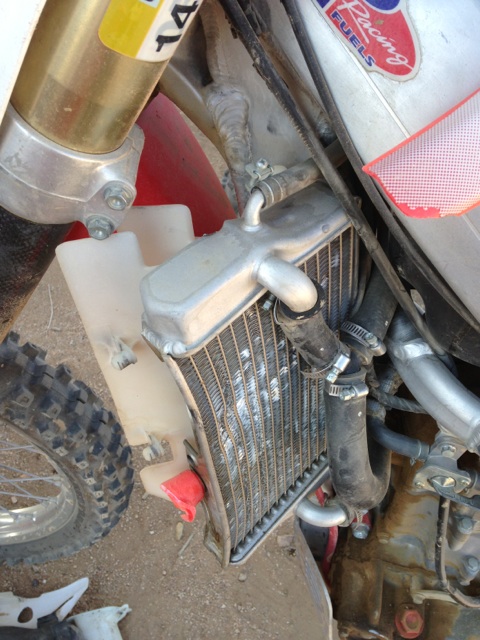 1986 Yugo GV - Close-up view of a dirt bike's radiator and coolant reservoir, with visible hoses and frame components.