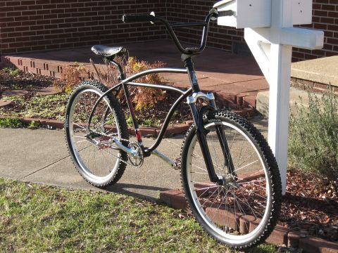 1994 Ford Bronco - A custom cruiser bicycle with a distinctive frame design is parked outdoors next to a brick house and a mailbox.