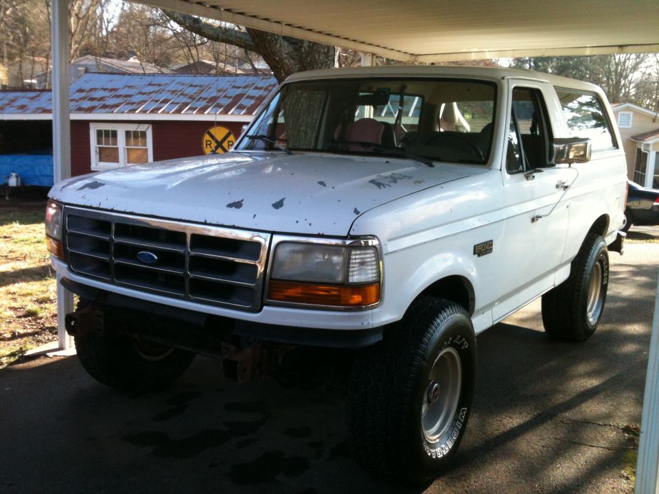 1992 Ford Bronco parked under a carport, front 3/4 view