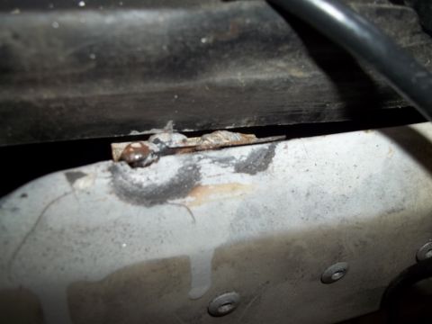 1990 Ford Bronco - Close-up of a rusted metal bracket and wire, likely from a vehicle's undercarriage or engine bay.