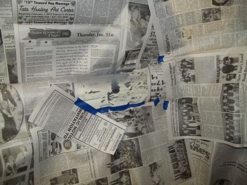 1990 Ford Bronco - A white car part is taped to a surface covered in newspapers.