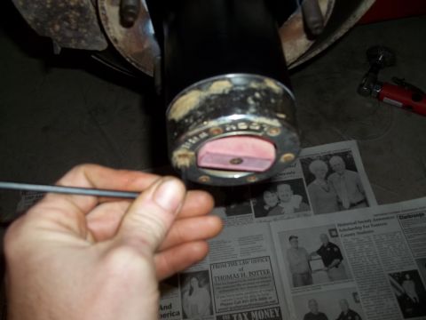 1990 Ford Bronco - Close-up of a vehicle hub assembly being worked on, with newspapers visible underneath.