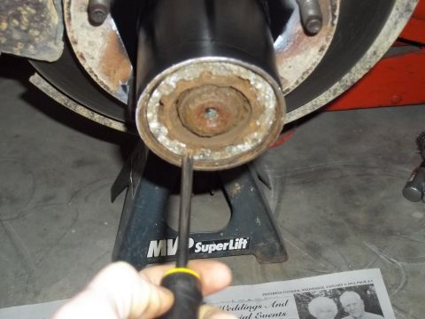 1990 Ford Bronco - A close-up view of a vehicle's wheel hub assembly, showing rust and wear, supported by a jack stand.