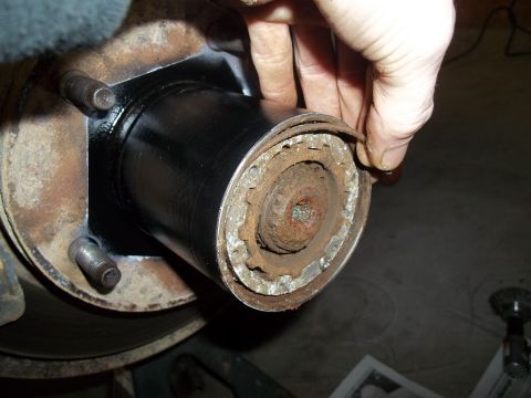 1990 Ford Bronco - A person is shown working on a vehicle's hub assembly, with a focus on the rusty components and a newly installed black part.