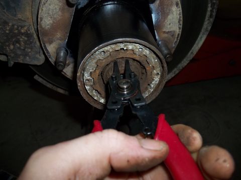 1990 Ford Bronco - Close-up of a wheel hub assembly with snap ring pliers in use.