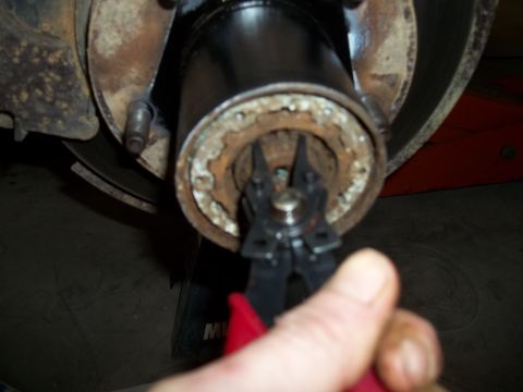 1990 Ford Bronco - Snap ring pliers are used to remove a snap ring from a wheel hub assembly.