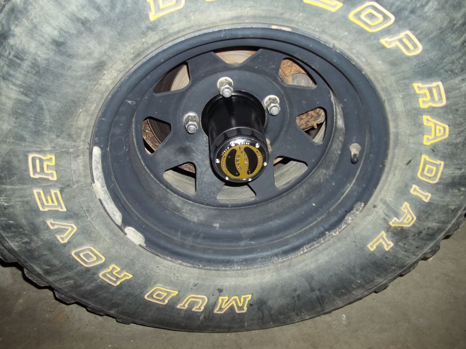 Close-up of a black wheel with a yellow lettered Dunlop Mud Rover radial tire and a black hubcap