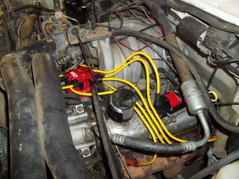1990 Ford Bronco - Close-up view of an engine's ignition system, a red MSD distributor and yellow spark plug wires.