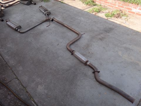 1995 Ford Taurus - Exhaust system components are displayed on a concrete surface, with visible pipes and mufflers.