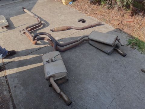 1995 Ford Taurus - Multiple exhaust system parts are visible, including mufflers and piping, on a concrete surface.