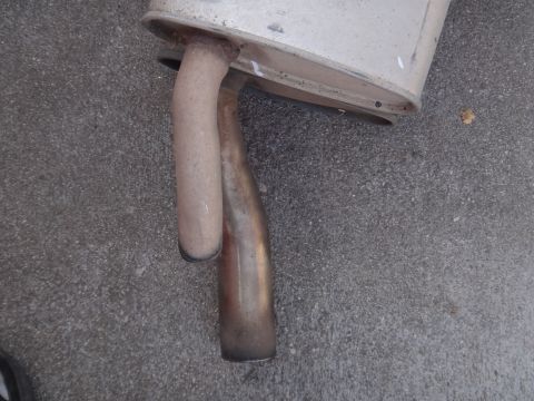 1995 Ford Taurus - Close-up of a vehicle's exhaust system components resting on a textured concrete surface.