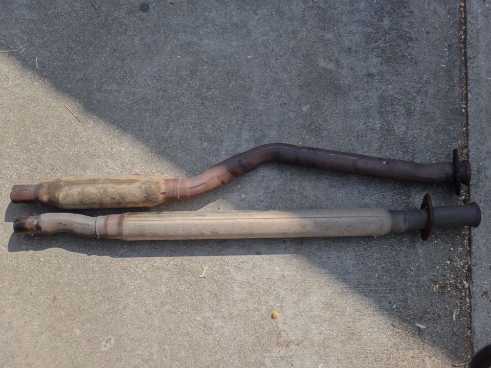 Two exhaust mufflers and pipes laid on concrete