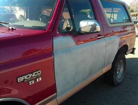1994 Ford Bronco - A red 1994 Ford Bronco is shown from the side, with its lower doors covered in primer.