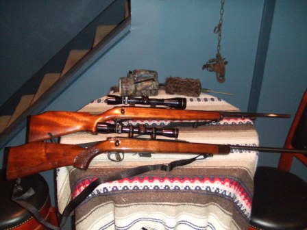 1996 Ford Bronco - Two hunting rifles are displayed on a table, each equipped with a scope.