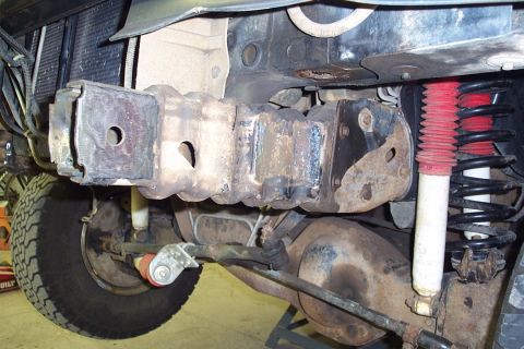 1996 Ford Bronco - Underside view of a Ford truck's front suspension and frame, showing a coil spring with red upper coils and a white-bodied shock absorber,…